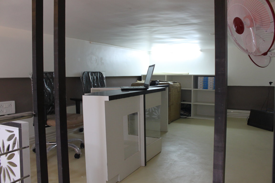 Upper-floor Insight Institute staff office with a working laptop counter, archive shelving and a wall-mounted pedestal fan